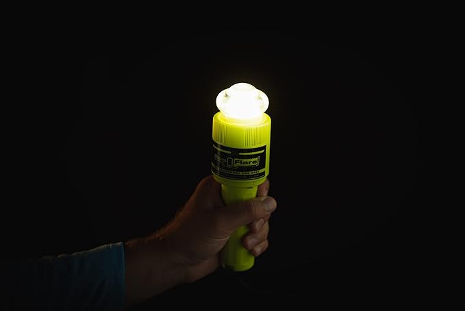 Hand holding ACR ResQFlare electronic distress flare glowing brightly in dark for emergency signaling